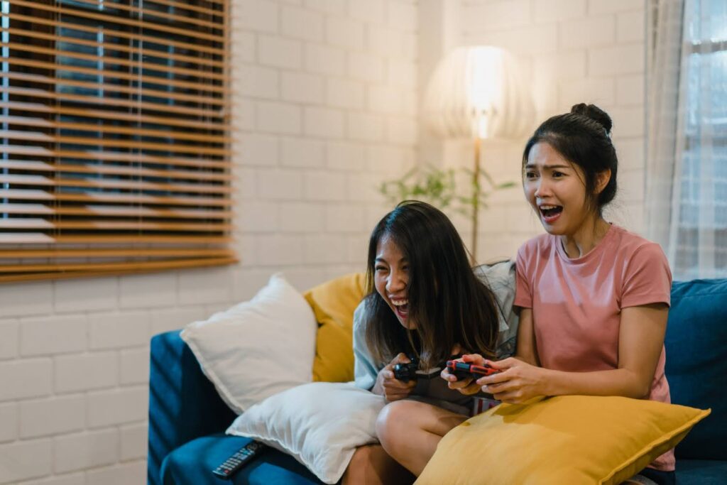 Two Southeast Asian women immersed in video game with controllers in their hands