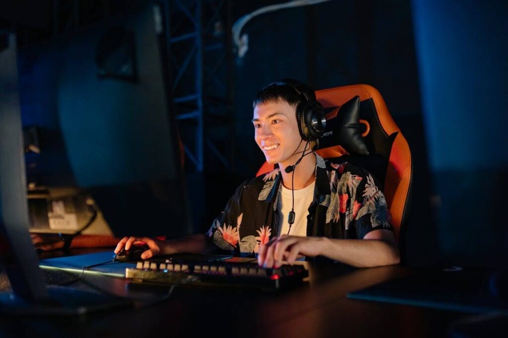 Young players from Southeast Asia immerse in gaming on PC with headset in dim light