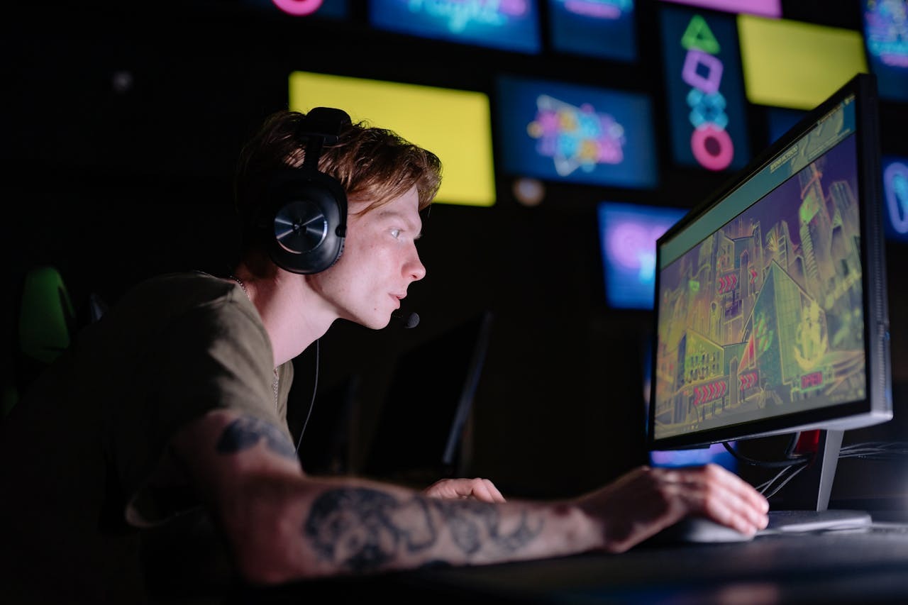 Focused beginner creator working at a gaming PC with a colorful game interface on screen
