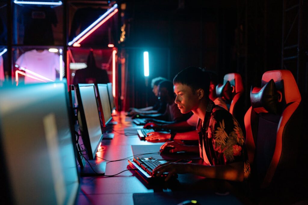 A row of players intensely playing on PCs with gaming chairs and headsets, competing in an eSports event.