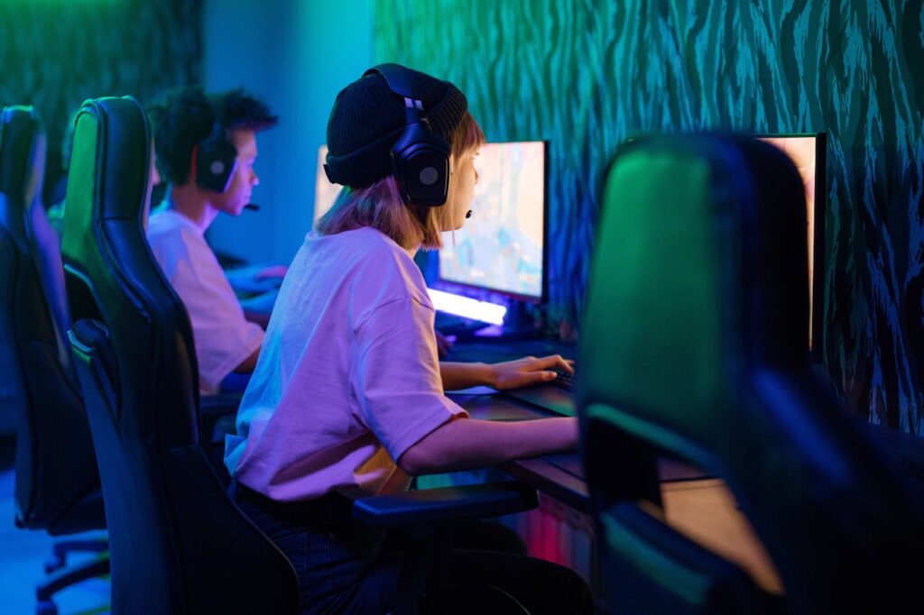 Teenagers in an internet café in Southeast Asia, each at individual computers, immersed in gaming in a dimly lit room.
