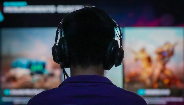 Back view of a gamer with headset, immersed in the game world through rich spatial sound and immersive audio design.
