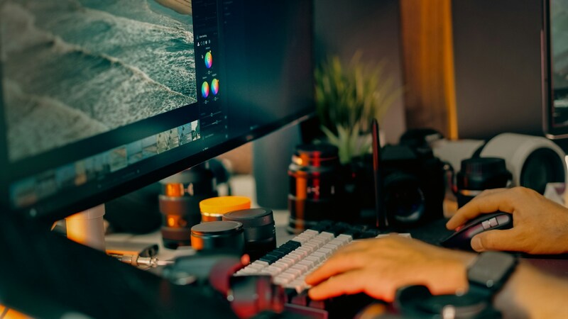 A close-up of a developer’s hands on keyboard, scanning a large monitor for bugs and glitches.