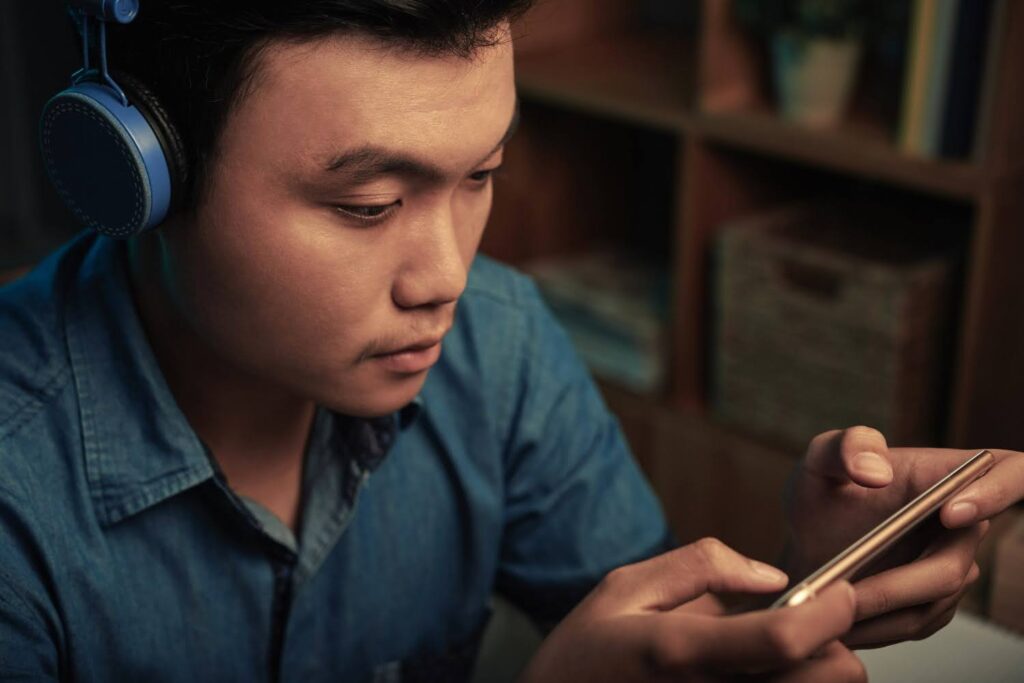 A male gamer is playing a localized mobile video game on his smartphone