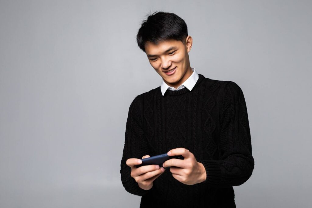 A male gamer enjoying a localized mobile game on his smartphone.
