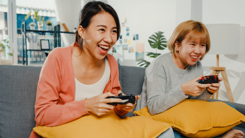 Two people enjoying a localized multiplayer game using controllers on a cozy sofa.