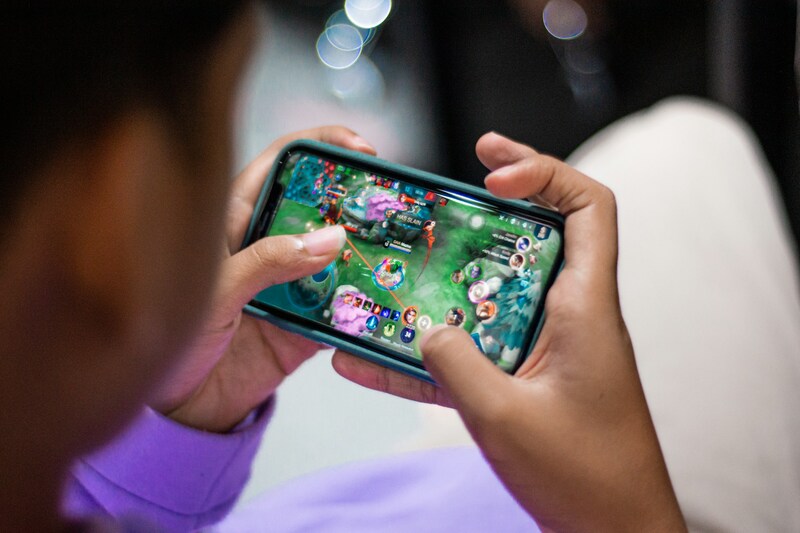 A gamer playing a multiplayer mobile game on smartphone and connecting with an online community.