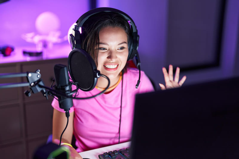 A female gamer uses a headset and mic, enjoying immersive game audio that improves focus and playtime.