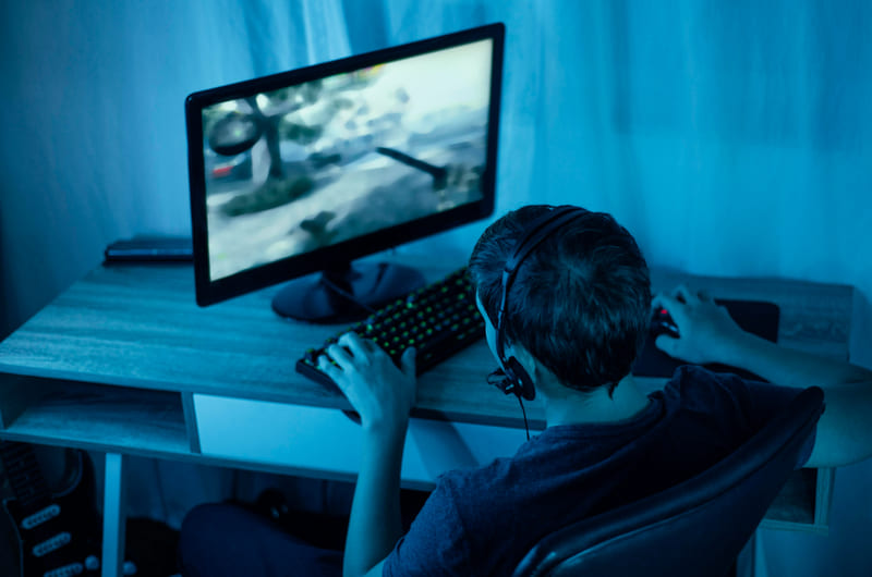 A young gamer plays on a PC, enjoying an intelligent AI game world.