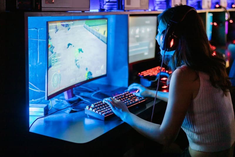 A woman playing a video game on a PC, showcasing hybrid game models and long-term growth.