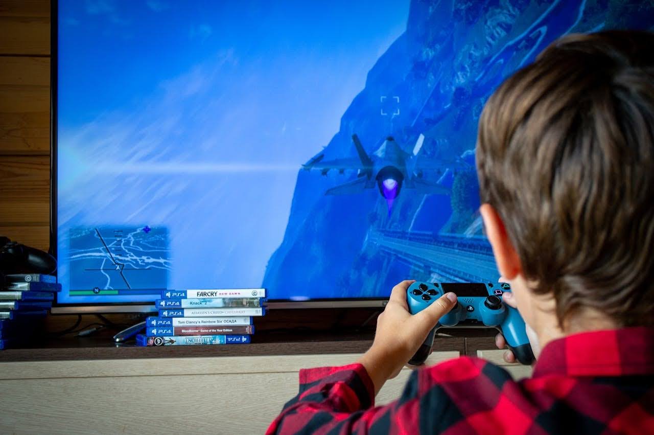A young gamer playing a video game on a large screen using a controller.