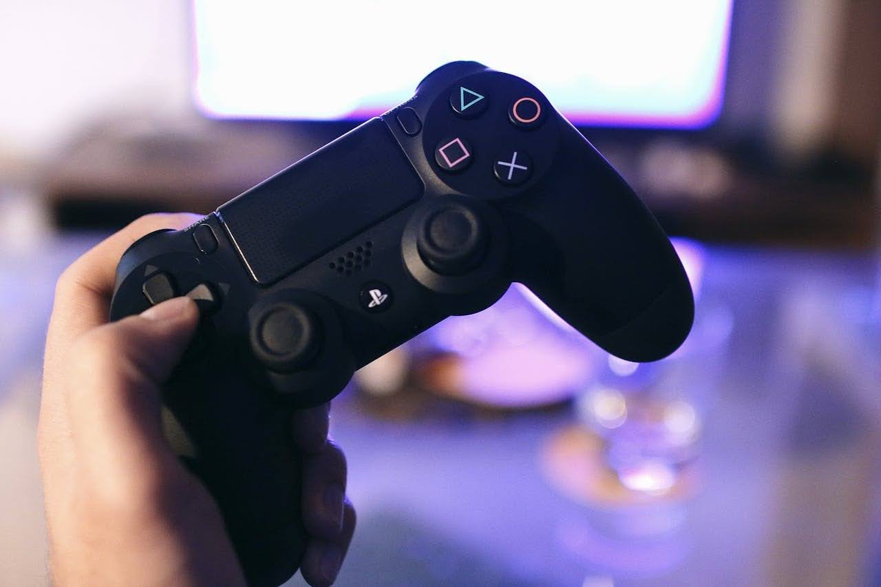 A gamer holding a PlayStation controller while playing a remake of a classic video game on a TV.