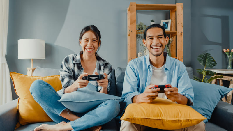 An illustration of two Indonesian gamers enjoying a competitive video game session on a TV screen.