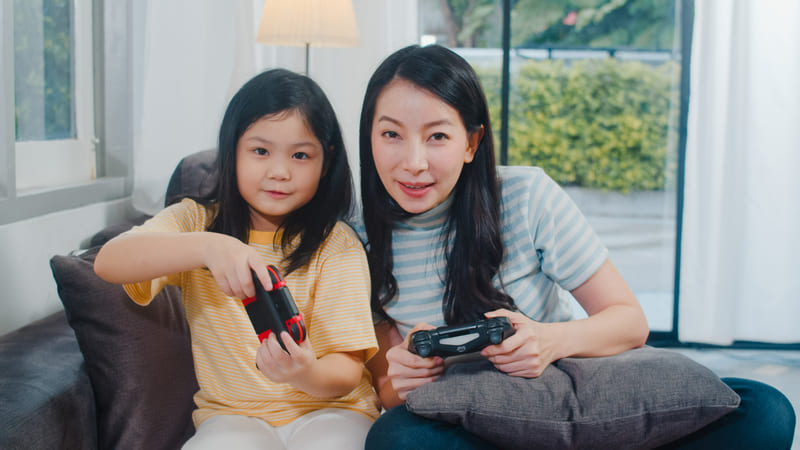 A mother and daughter play video games together, showing how age labels promote safe and appropriate games for young players.