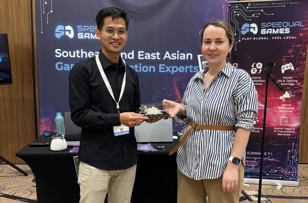 Anastasiia Nikolaieva from G5 Games receiving a special grand door prize from a SpeeQual Games representative at the SpeeQual Games booth during the Game Quality Forum Global 2026