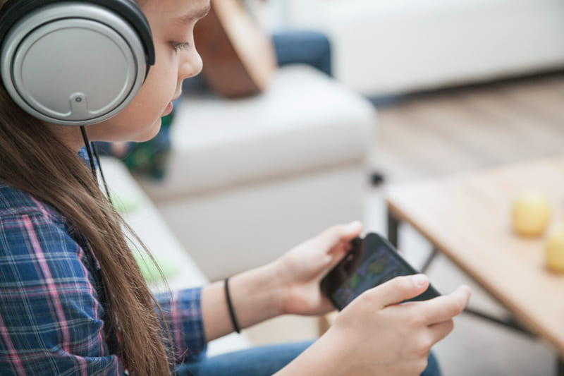 A young girl wearing headphones, navigating a localized game with translated audio