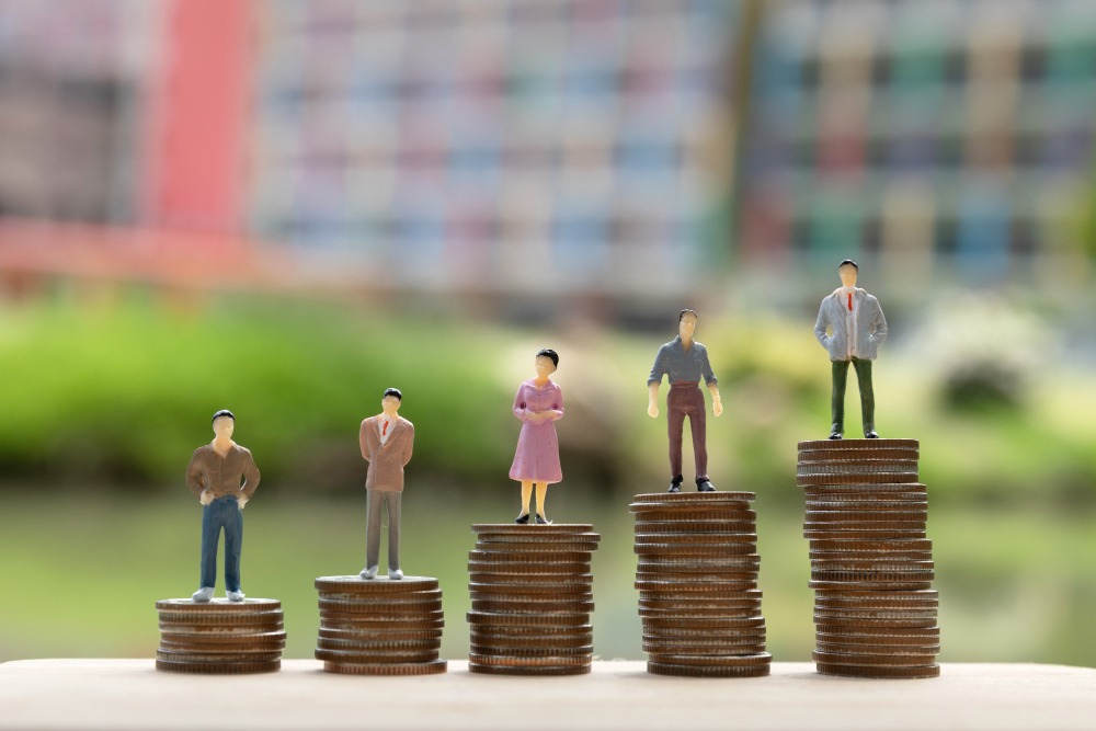 Miniature human figurines standing on stacks of coins of varying heights, symbolizing the diverse creator economies and revenue tiers across Southeast Asia.