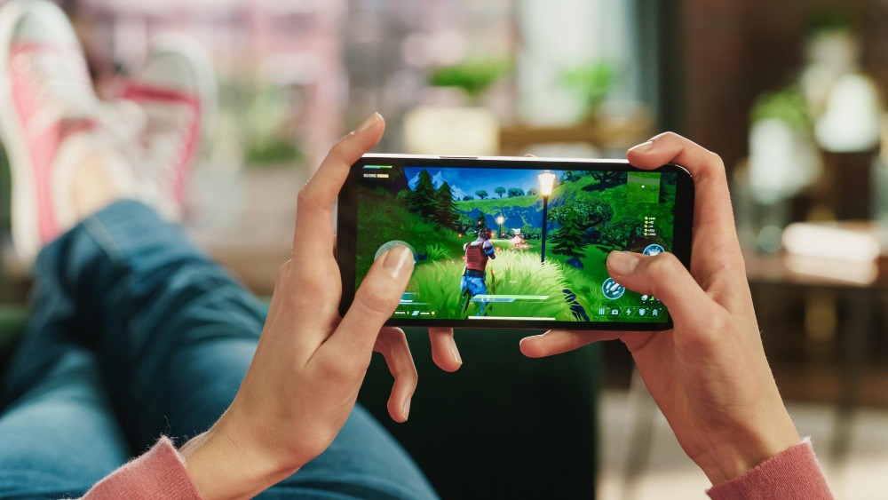 A gamer playing on a smartphone, highlighting the importance of mobile game localization testing in Thailand.