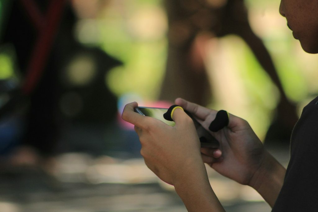 A gamer fully immersed in an MLBB match on smartphone.