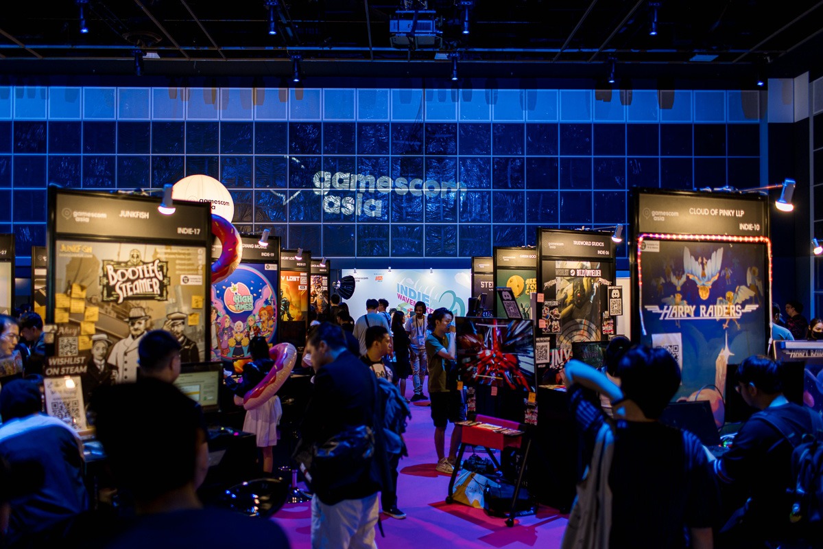 A crowded exhibition hall at gamescom asia filled with gaming fans and colorful booth displays.