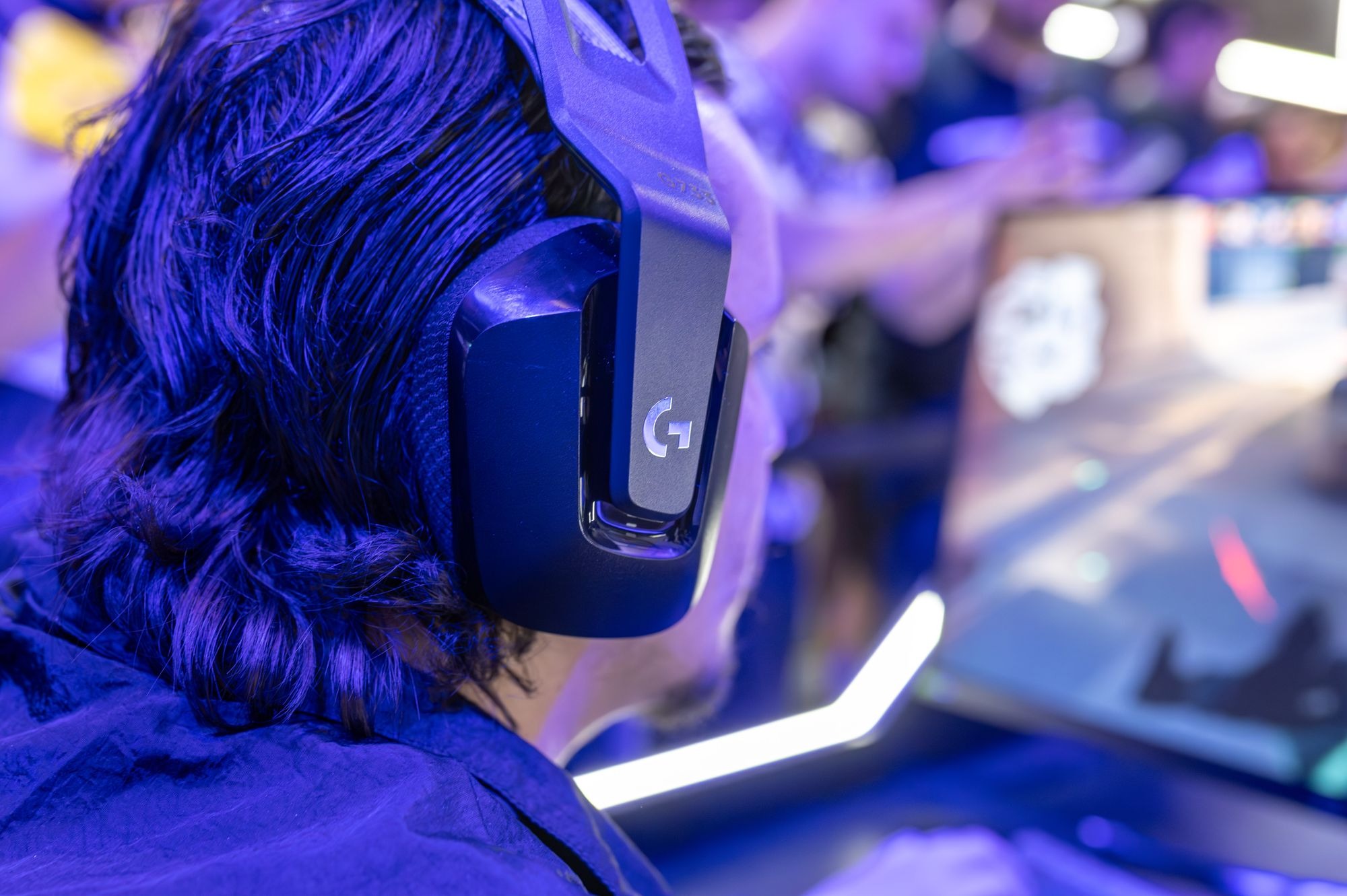 Back view of a gamer wearing a gaming headset, focused on a game stream on PC.